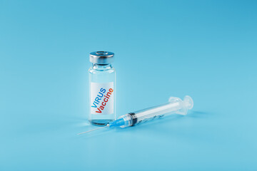 Ampoule of vaccine medicine with a syringe on a blue background.