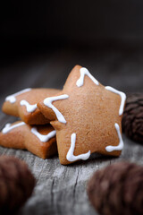 Christmas cookies in the shape of a star with white icing and pine cones on an old wooden background. Space for text. Vertical image.