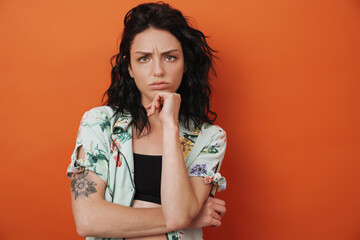 Sad woman isolated over orange wall background