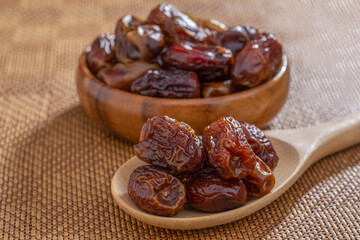 dried dates in a wooden bowl on wood table background.