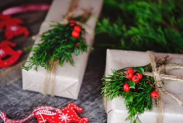 Christmas presents decorated with branch of cotoneaster and green pine branch on wooden old background