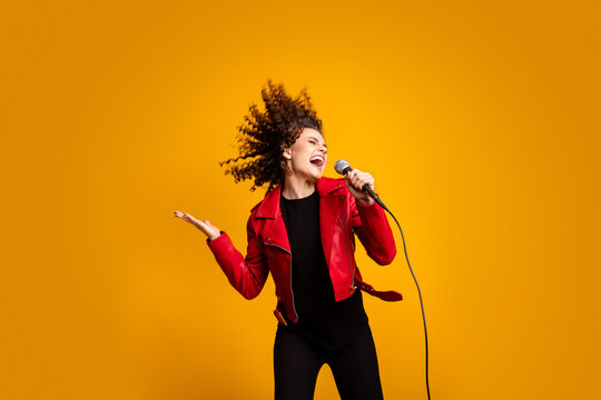 Portrait of attractive popular wavy-haired girl solist vocalist singing hit isolated on bright yellow color background