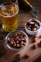 A glass of beer and smoked salted nuts on a wooden background. Beer snack.