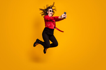 Fototapeta na wymiar Full length body size view of lovely cheerful wavy-haired girl jumping having fun using device isolated on bright yellow color background