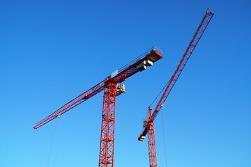 Zwei Kräne auf Baustelle vor blauem Himmel