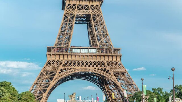 Close up view of first section of the Eiffel Tower with tourists on observation deck timelapse in Paris, France. Sunny summer day with blue clody sky