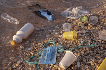 Plastic debris and face masks on the beach. Coronavirus COVID 19 is contributing to pollution, as...