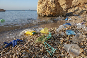 Plastic debris and face masks on the beach. Coronavirus COVID 19 is contributing to pollution, as...