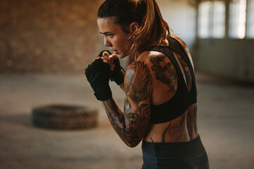 Female doing shadow boxing in empty factory shade