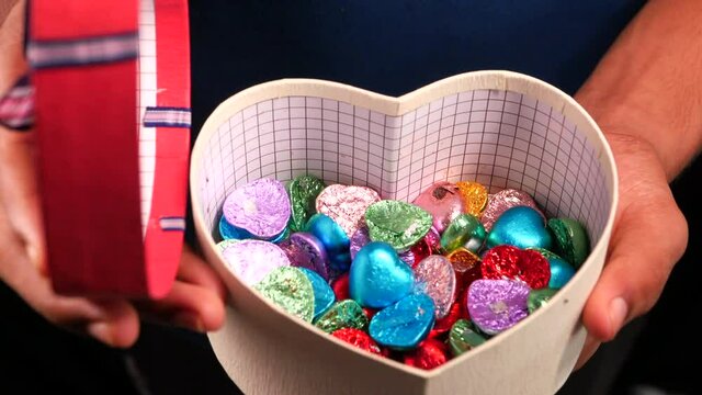 close up of man hand opening a gift box full of candy 