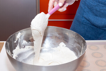 The process of mixing the batter with a spatula in a metal bowl. Cooking macaroon dessert.