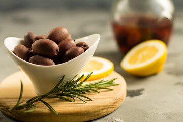 olives with lemon in a white plate, on a wooden board