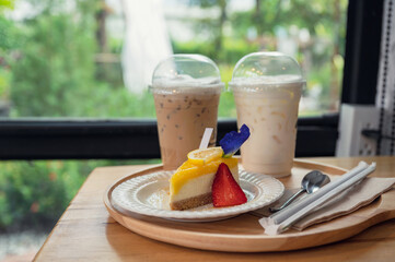 Lemon cake with biscuit and ice coffee on wooden tray
