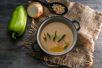 Pea soup in a bowl near sperm and onions on a wooden table