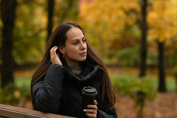 a girl in the Park in autumn drinks coffee and enjoys nature
