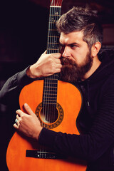 Obraz premium Handsome bearded man playing guitar at the pub. Practicing in playing guitar. Hipster guy playing guitar.