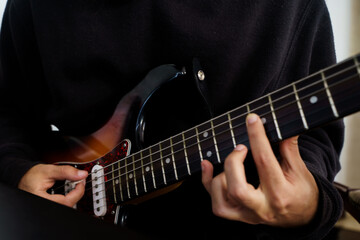 Boy playing a beautiful electric guitar of various colours with his hands