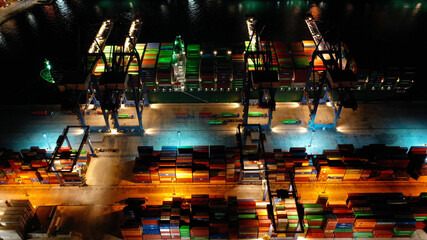 Obraz premium Aerial drone night shot of illuminated loading/unloading container terminal in commercial port of Perama, Piraeus, Attica, Greece