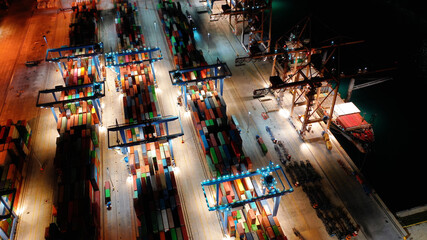 Aerial drone night shot of illuminated container terminal facilities in popular Mediterranean logistics port