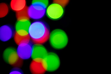 A brilliant glowing background side on black. The glitter light bokeh for the New Year and other holidays. Place for text copyspace.