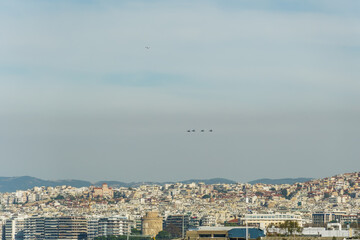 Fototapeta na wymiar F-16 fighter jets flying above a city landscape. Greek Air Force aircrafts on formation above Thessaloniki at October 28, day commemorating the Hellenic no against the Italian 1940 ultimatum.