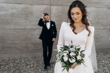 The bride is dressed in a white wedding dress with a wedding bouquet of white peony roses and...