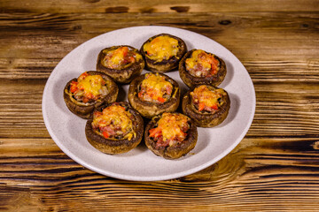 Baked champignons stuffed with minced meat and cheese in plate on a wooden table
