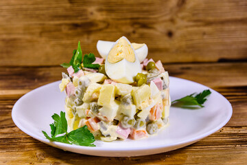 Ceramic plate with russian traditional new year salad olivier on a wooden table