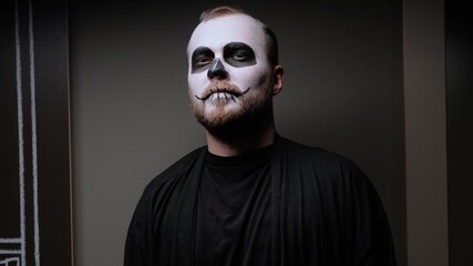 A zombie man with makeup on his face is standing against the wall. Halloween Eve