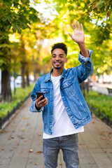 Happy african man waving hand on hello gesture looking at camera standing in the street © F8  \ Suport Ukraine