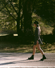 Trendy girl in the woods wearing a black dress and a fedora hat during autumn in Spain.