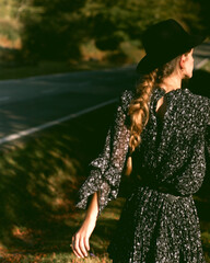 Trendy girl in the woods wearing a black dress and a fedora hat during autumn in Spain.