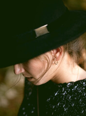 Trendy girl in the woods wearing a black dress and a fedora hat during autumn in Spain.