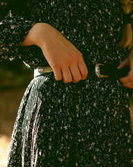 Trendy girl in the woods wearing a black dress and a fedora hat during autumn in Spain.