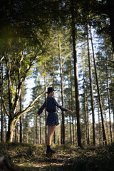 Trendy girl in the woods wearing a black dress and a fedora hat during autumn in Spain.