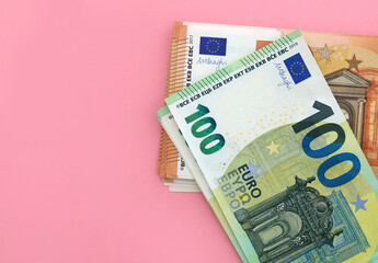 Pack of 100 euro and 50 euro banknotes at pink background