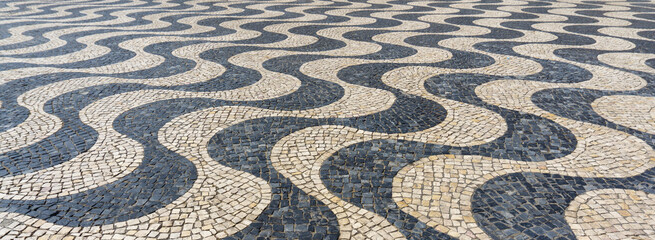 Typical Portuguese black and white stone mosaic calçada pavement in Cascais, Lisbon, Portugal....