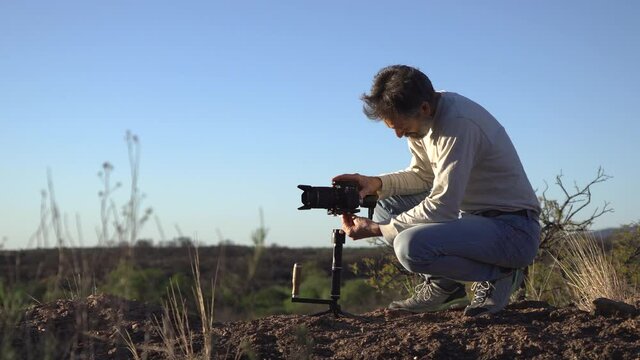 filmmaker preparing to film in nature with camera stabilizer. Man working on audiovisual production