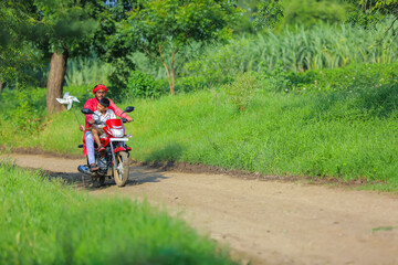 Young indian farmer dropping his child to school.