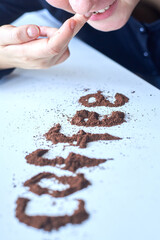A woman rubs coffee into her gums like a drug addict.