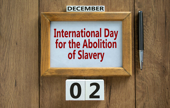 Picture frame with inscription 'International Day for the Abolition of Slavery' on beautiful wooden table, metalic pen and wooden calender with date december 02. Concept.