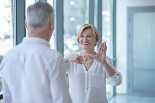 Blonde female having conversation with gray-haired male using sign language