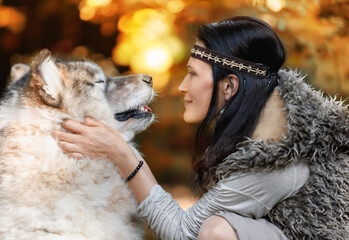 Portrait of a young woman with an Alaskan Malamute dog in the forest