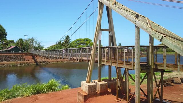 4K left to right panning motion of woman crossing the Hanapepe swinging bridge, Wooden bridge built in early 1900,Kauai,Hawaii,USA