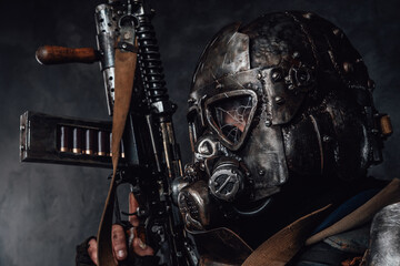 Headshot of ragged stalker in helmet with broken glass and custom armour with riffle in dark background.