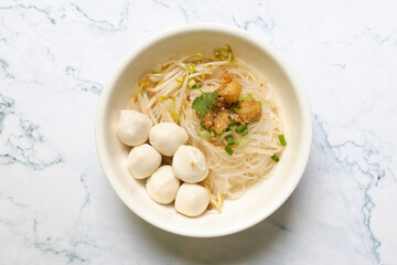 Rice stick noodles with fish ball and garlic cracklings with lard in white bowl. 