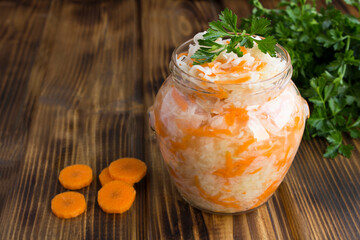 Sour cabbage in the glass jar on the wooden background