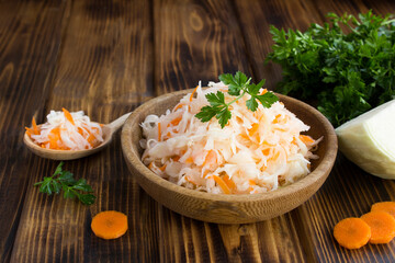 Closeup on sour cabbage in the brown bowl on the wooden background
