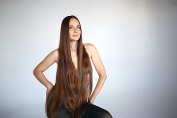 young beautiful woman with very long hair sits on a chair