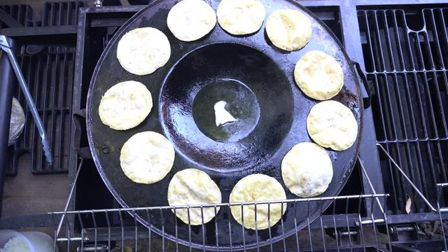 Top view of tortillas sitting in a hot comal with melting lard to make chalupas